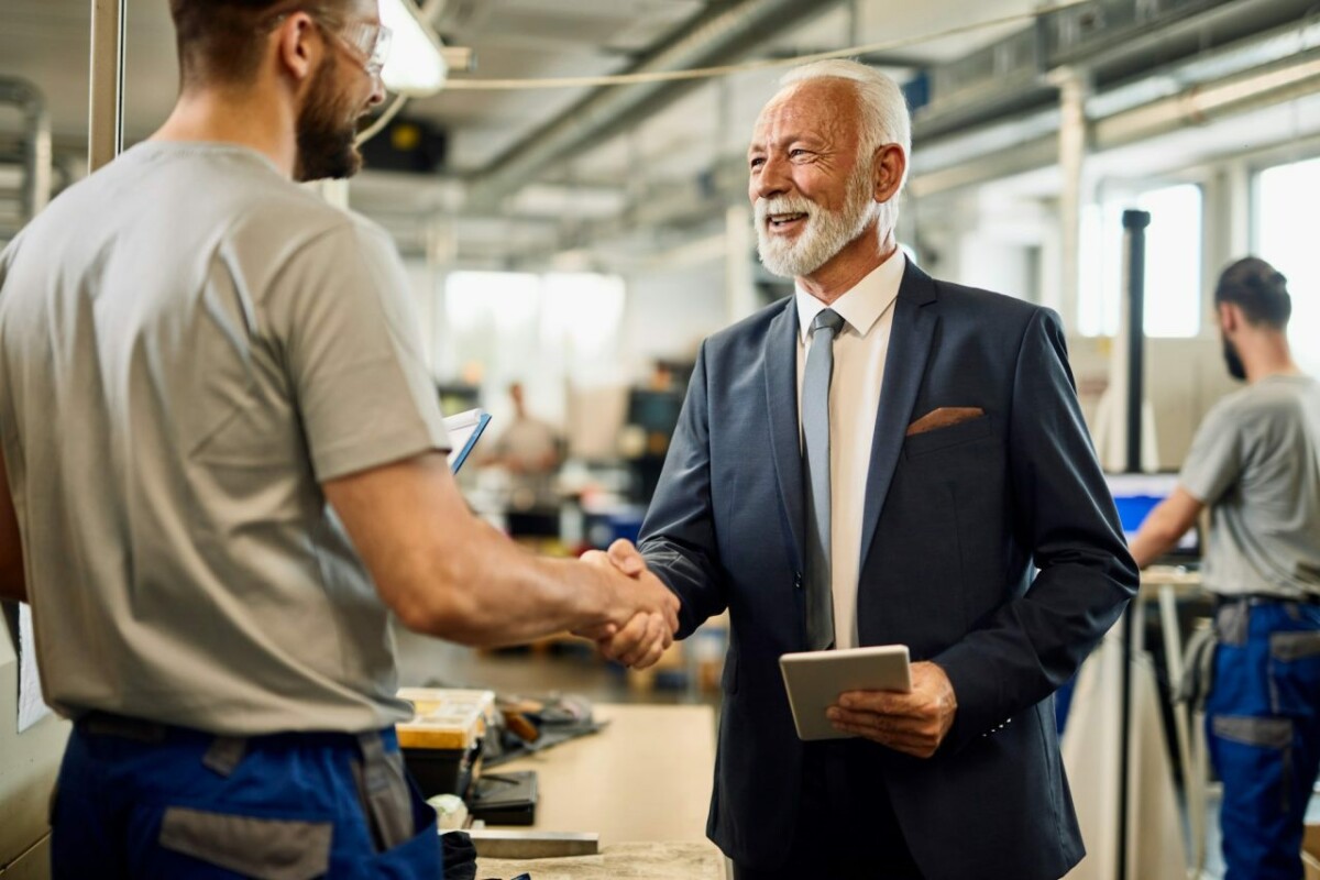 Happy senior businessman handshaking with manual worker in a factory .jpg